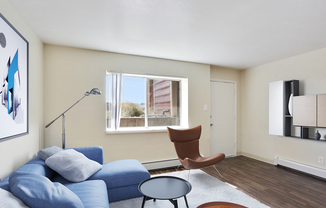 Bright and inviting living room with a modern blue sectional sofa, stylish leather chair, and wall art complementing natural light through a large window.