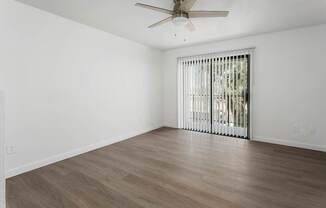 A room with a ceiling fan and a window with blinds.