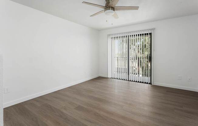 A room with a ceiling fan and a window with blinds.