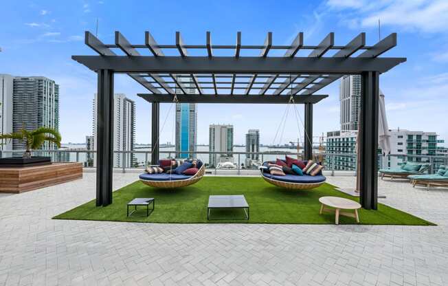 a rooftop lounge area with lounge chairs and a hammock with a view of the city