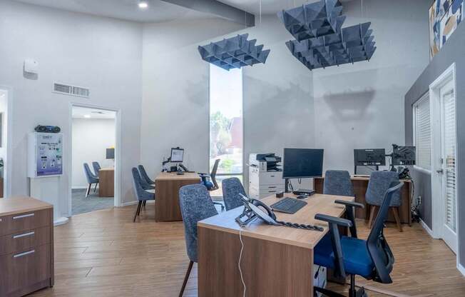 A modern office space with wooden desks and blue chairs.