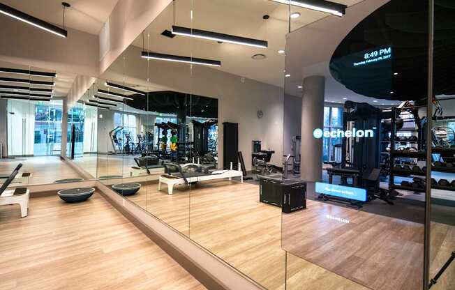 A gym with a mirrored wall and wooden floors.