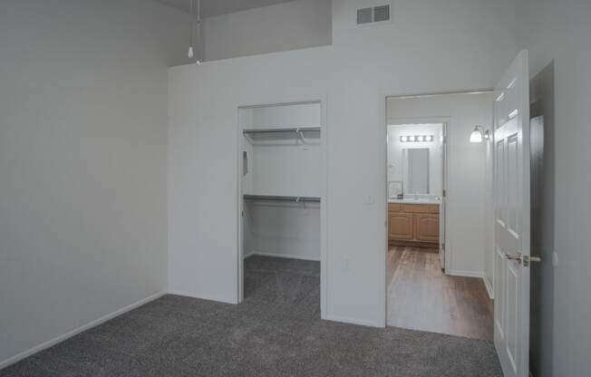 an empty living room with a hallway to a bathroom and a kitchen