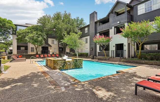 A swimming pool surrounded by a patio and buildings.