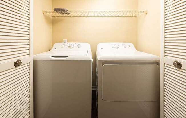 Two white washing machines in a small laundry room.