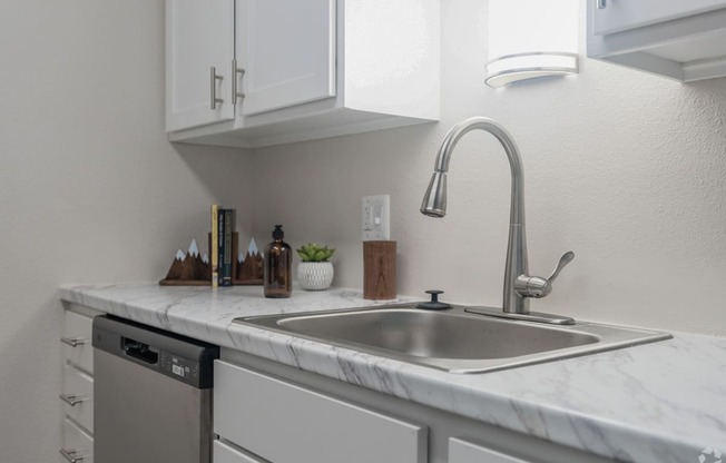 a kitchen with white cabinets and a stainless steel sink