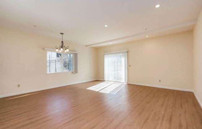 A large empty room with wooden floors and a chandelier.