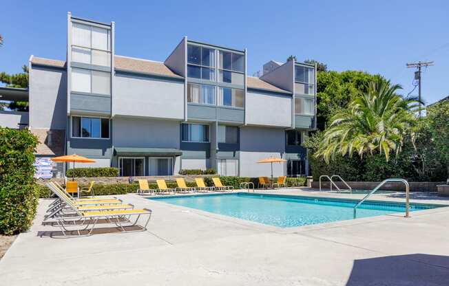 a swimming pool with chairs in front of a building