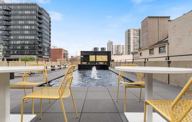 a patio with yellow chairs and tables on top of a building