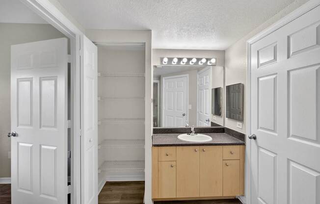 A bathroom with a sink, mirror, and cabinets.