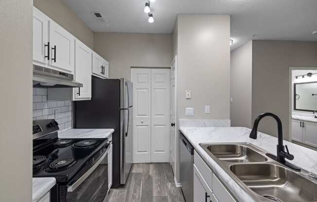 an empty kitchen with white cabinets and stainless steel appliances