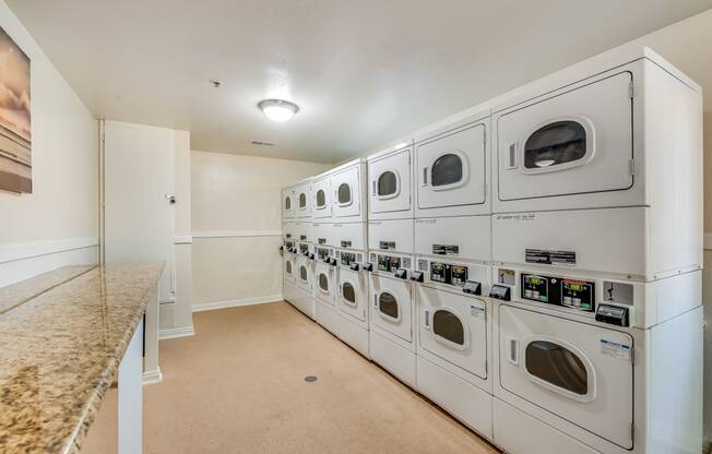a washer and dryer room at the enclave at woodbridge apartments in sugar land,