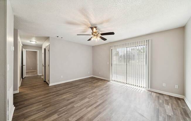 A room with a ceiling fan and sliding glass doors.