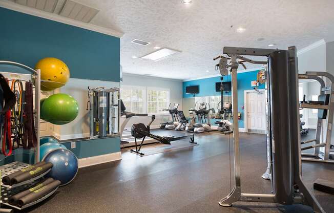 A gym with a variety of equipment including a weight machine, a treadmill, and a rowing machine.