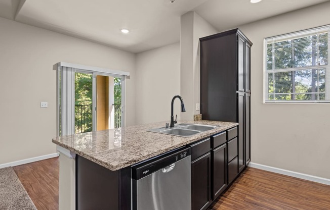 Little Tuscany Apartments & Townhomes - Kitchen Cabinets with Dark Color, Stainless Steel Appliances, Vinyl Wood Plank Flooring, White Woodwork, Granite Countertops, Breakfast Bar