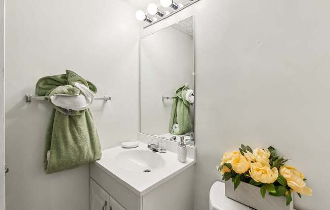 A white bathroom with a green towel hanging on the wall.