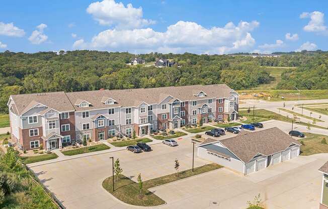 A large apartment building with a parking lot and garages in front at Strathmore Apartment Homes, West Des Moines, IA
