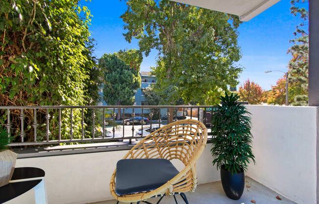 a balcony with a rattan chair and a plant on it