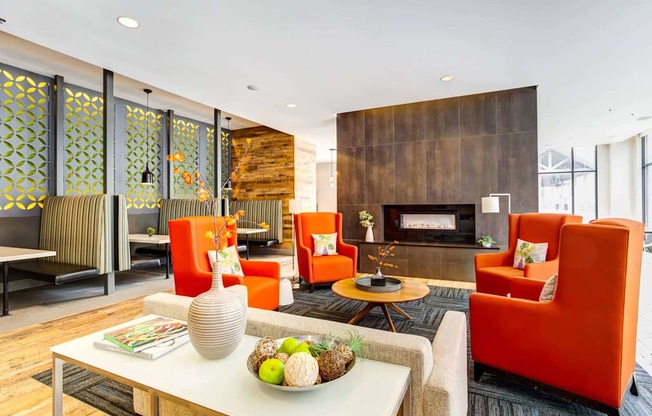 A living room with a fireplace and orange chairs.