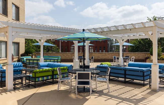 a patio with blue couches and green couches under a white pergola