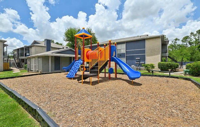 A playground with a blue and orange slide in the foreground.