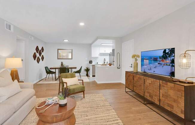 A living room with a white couch, a wooden coffee table, and a TV on a wooden cabinet.