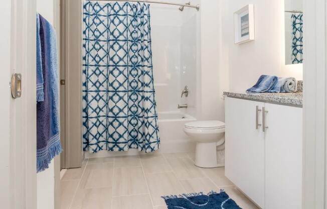 a bathroom with a white toilet and a blue shower curtain