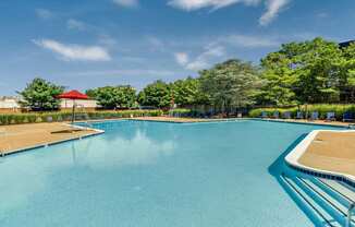 A large swimming pool with a red roof and trees in the background.