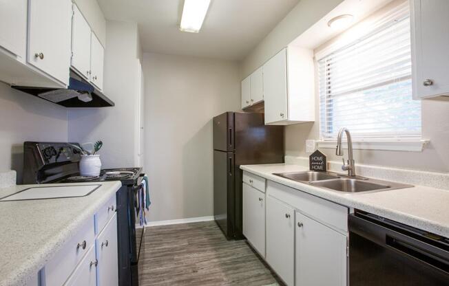 A kitchen with white cabinets and a black refrigerator.