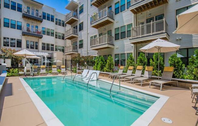 A large swimming pool in front of apartment buildings.