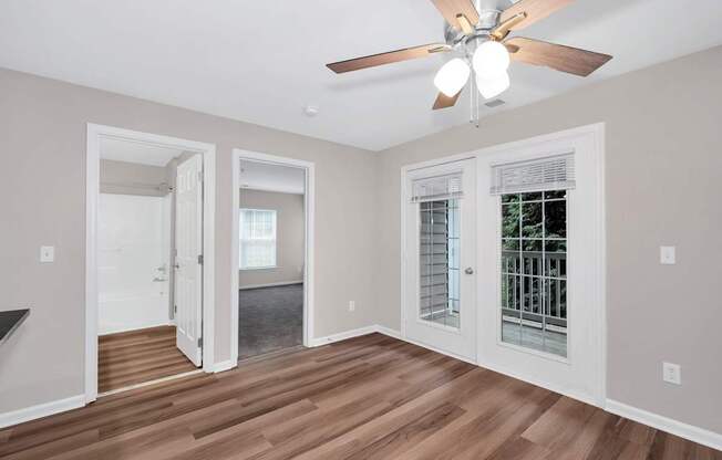 A room with a ceiling fan and wooden floors.