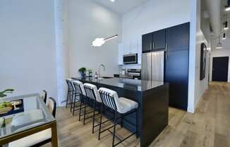 a kitchen with a long island with bar stools and a black