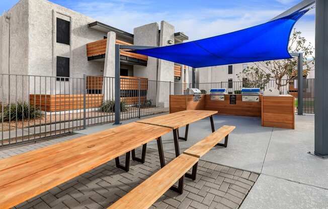 a picnic table with a blue awning in front of a building