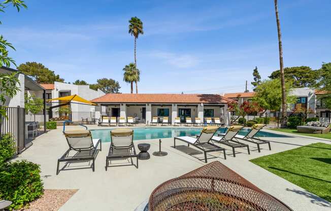 a swimming pool with chaise lounge chairs and a clubhouse in the background