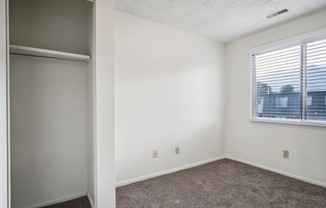 an empty bedroom with a window and a closet