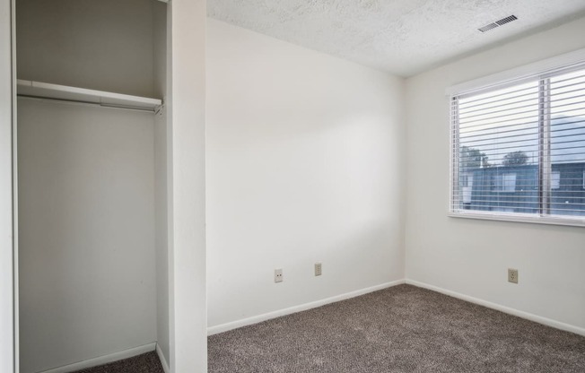 an empty bedroom with a window and a closet