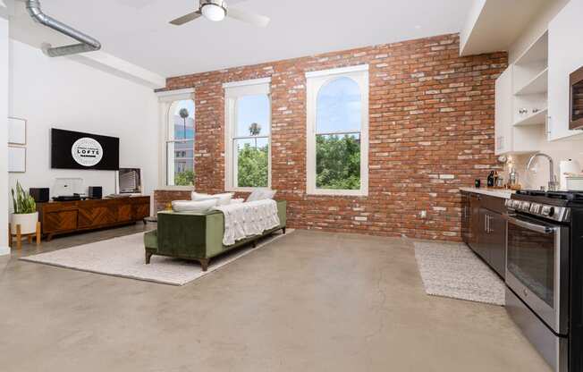 a living room with a couch and a brick wall and a kitchen with a stove