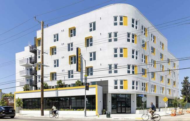 A white building with yellow accents sits on a street corner.