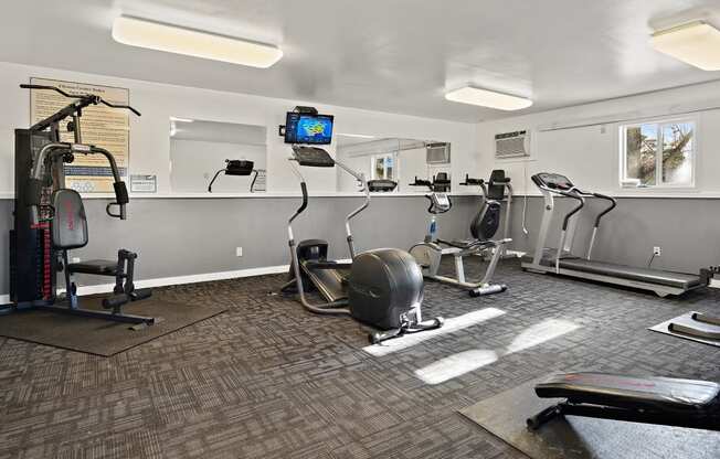 a gym with exercise machines and a tv on the wall