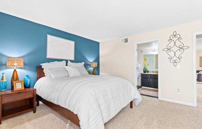 a bedroom with a bed and a blue wall and a bathroom