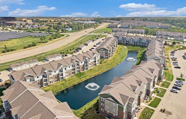 A large apartment complex with a pond in the middle at Strathmore Apartment Homes, West Des Moines, IA
