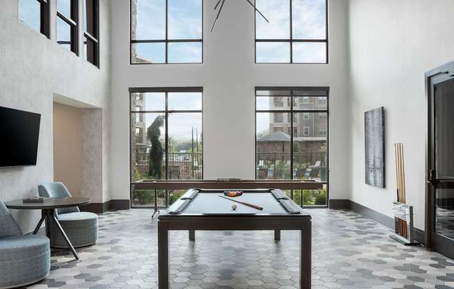 A billiard table is in the middle of a room with a television and a chair.