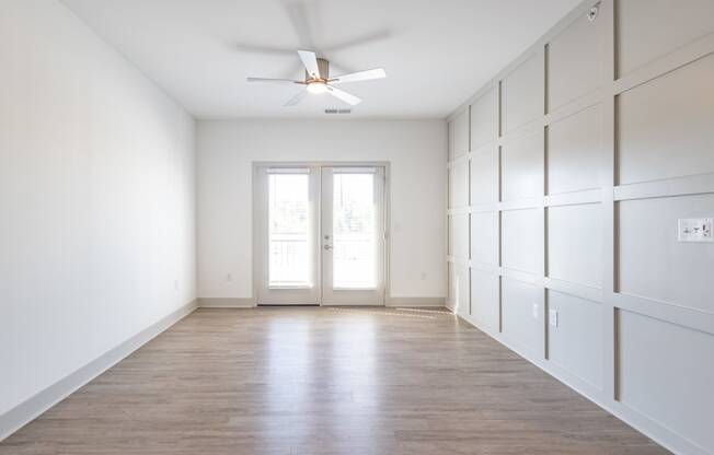 an empty room with white walls and a ceiling fan