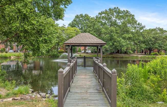 A wooden pier leads to a gazebo over a lake surrounded by trees.