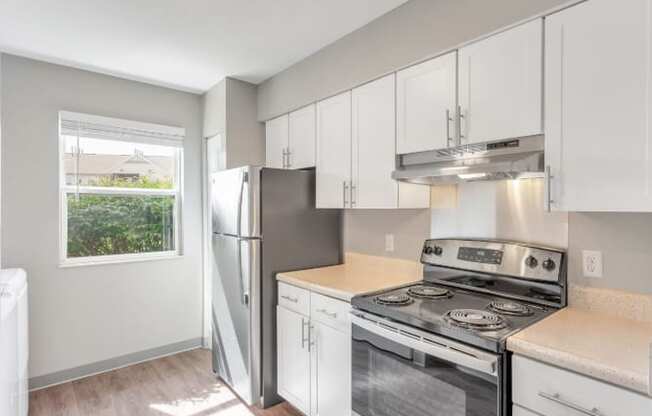 A kitchen with a stove, refrigerator, and cabinets.