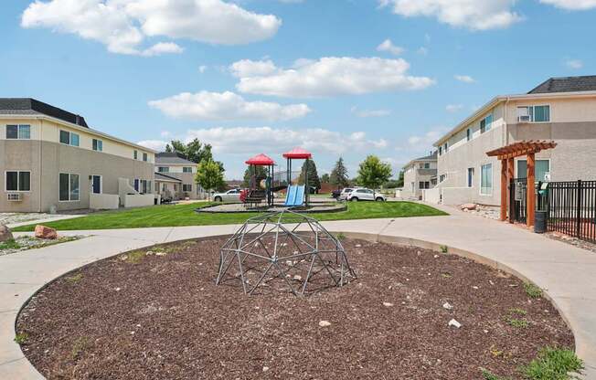 A playground with a swing set in the middle of a mulched area.