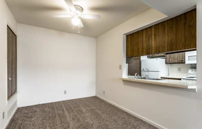 an empty room with a kitchen and a ceiling fan