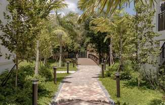 a wooden bridge over a brick path in a park