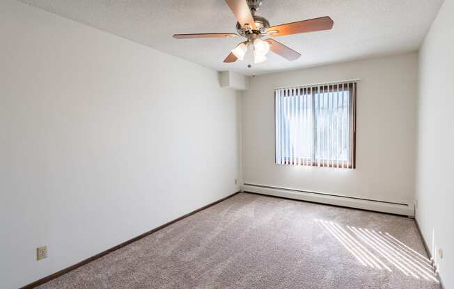 a bedroom with a ceiling fan and a window. Eagan, MN Glen Pond Apartments