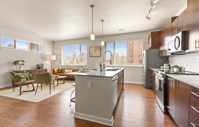 Spacious kitchen with hardwood flooring and an island with view into well-decorated living room at Sylvan Uptown, Colorado, 80203